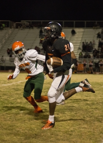 Chaparral‘s Casey Acosta (21) runs the ball while pursued by Mojave‘s Kevin John ...