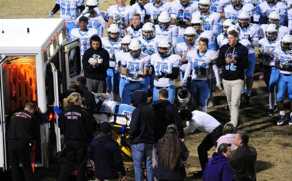 Foothill players meet at the rear of an ambulance to give encouragement to junior defensive ...