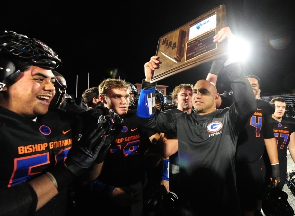 Bishop Gorman head coach Kenny Sanchez, right, hoists the NIAA Sunset Region Championship tr ...