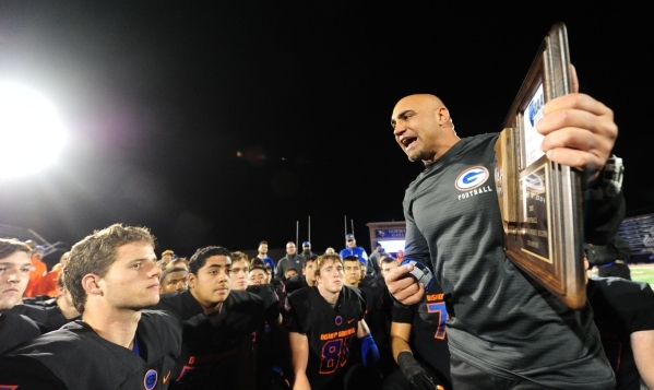 Bishop Gorman head coach Kenny Sanchez, right, addresses his players while holding the NIAA ...