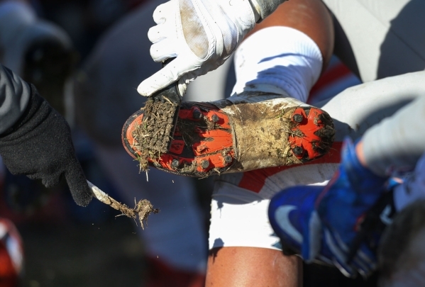 Bishop Gorman players scrape mud off their cleats during an NIAA Division I playoff game at ...