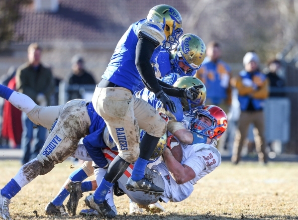 Bishop Gorman‘s Jonathan Shumaker gets tackled by a wave of Reed defenders in an NIAA ...