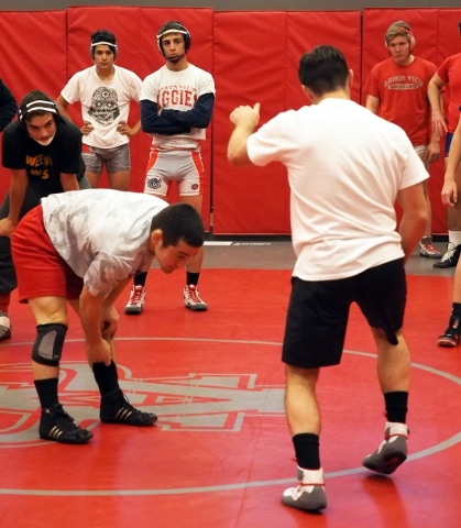 Wrestler Lawrence Vigil, center rear, watches Coach Rusty Marchello, back to camera, demonst ...