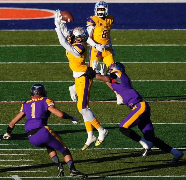 Sunrise All-Stars wide receiver Devion Clayton, center, of Silverado High School, tries to m ...