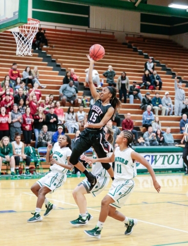 Desert Oasis freshman Ahmaya Smith (15) leaps up to make a basket while surrounded by Green ...