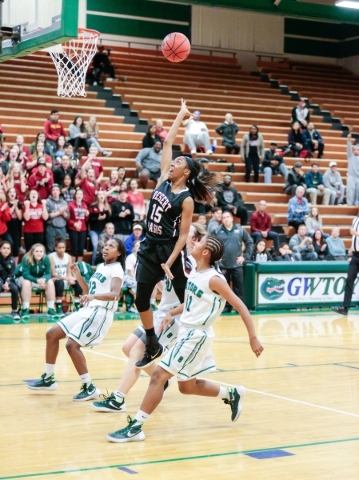 Desert Oasis freshman Ahmaya Smith (15) leaps up to make a basket while surrounded by Green ...