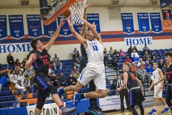 Bishop Gorman center Zach Collins (12) takes the ball to the basket while being defended by ...