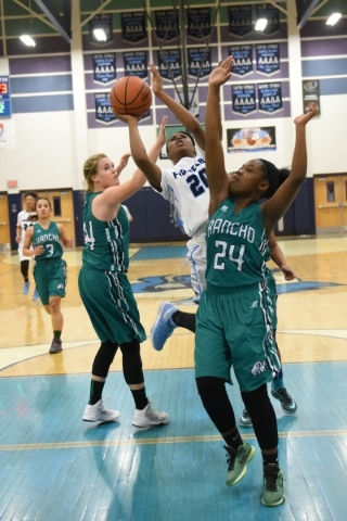 Canyon Springs Alexia Thrower (20) goes up for a shot against Rancho defenders Samantha Poch ...