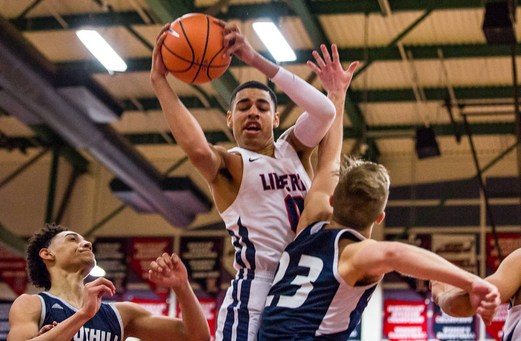 Liberty’s Julian Strawther (0) struggles to put up a shot while Liberty defenders Mike ...