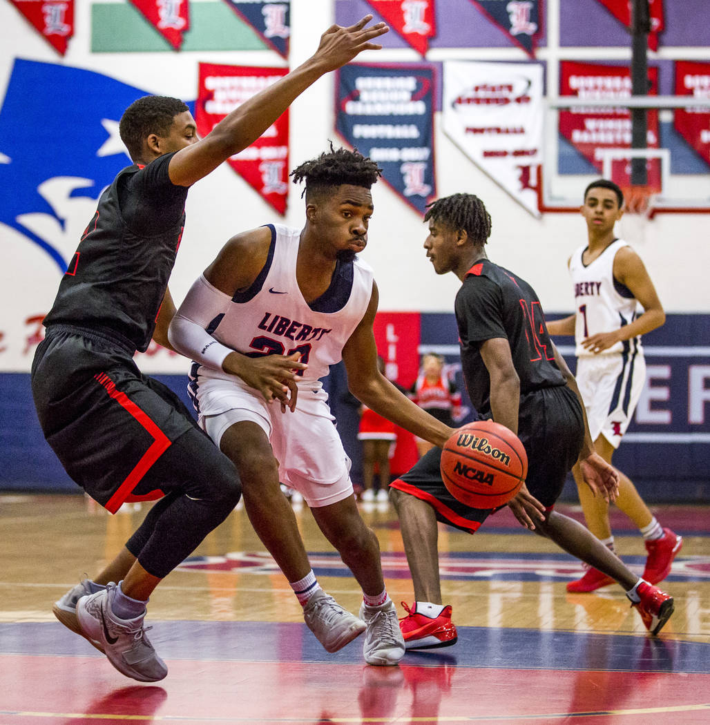 Liberty’s Davion Ware (23) attempts to keep the ball away from Las Vegas defenders Zio ...