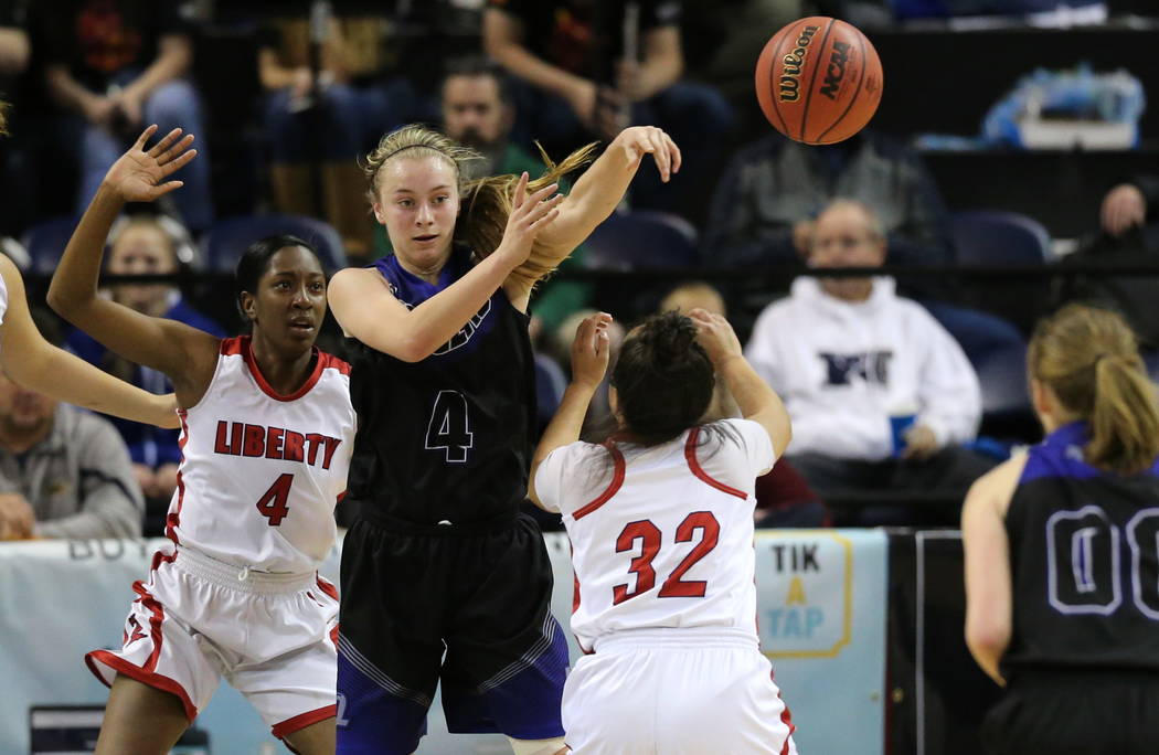 McQueen’s Kendra McAninch passes around Liberty defenders Robin Walker, left, and Tedr ...