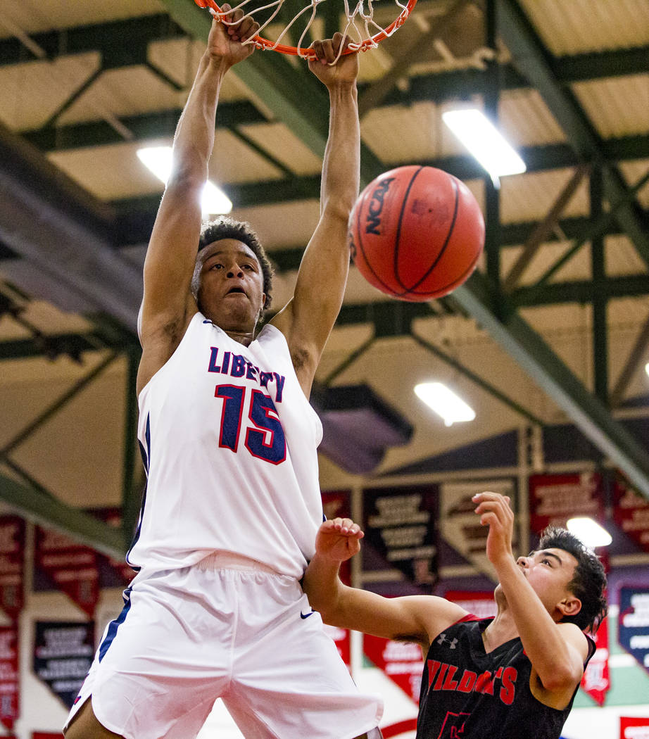 Liberty’s Cameron Burist (15) completes an alley-oop while Las Vegas’ Adam Pascq ...