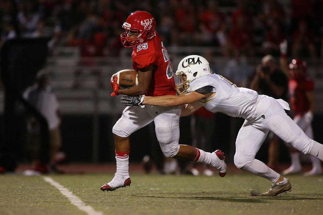 Arbor View player Kyle Graham (25) attempts to run the ball as Faith Lutheran player Keagan ...