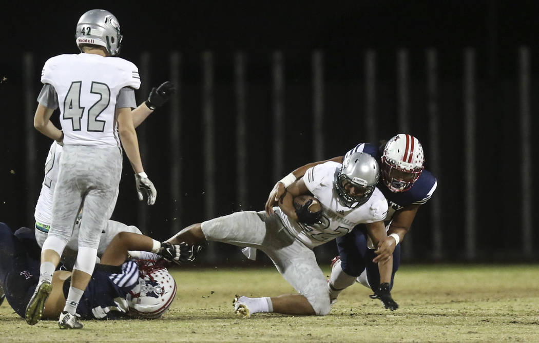 Green Valley running back Julian Hulse (22) is tackled by Liberty’s Tamakave Tai (20) ...