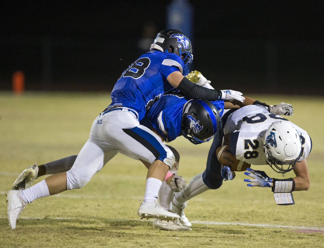 Foothill wide receiver Braeden Wilson (28) is tackled by Basic defenders Tommy Paonessa (4), ...