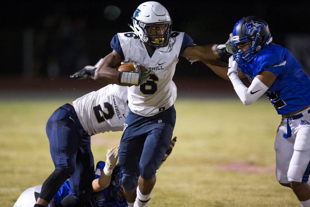 Foothill’s Jordan Wilson (6), center, stiffs arms Basic’s Christopher Render (2) ...