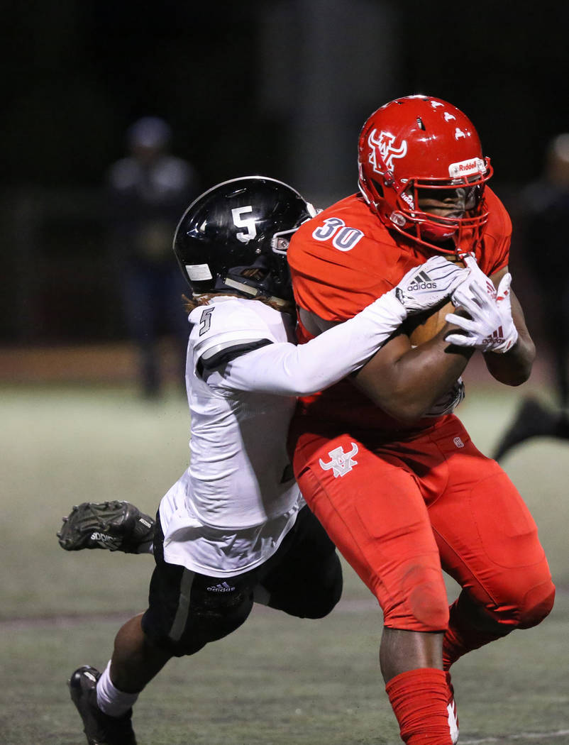 Arbor View’s Darius Williams (30) protects the ball while being tackled by Desert Pine ...