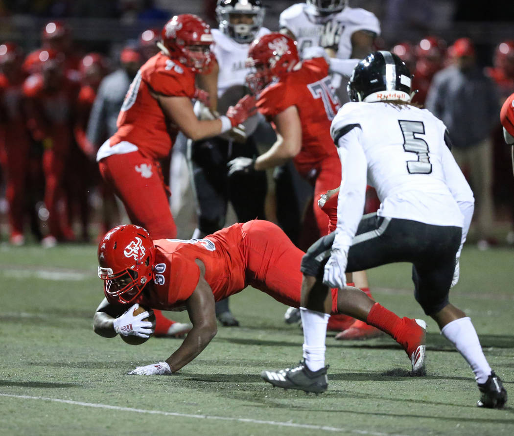 Arbor View’s Darius Williams (30) goes down with the ball while under pressure from De ...