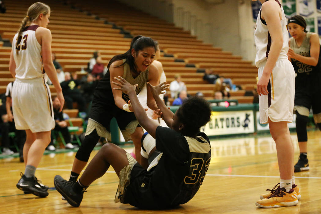 Spring Valley’s Chyna Charles (33) gets help getting up from Chelsea Camara (5) after ...