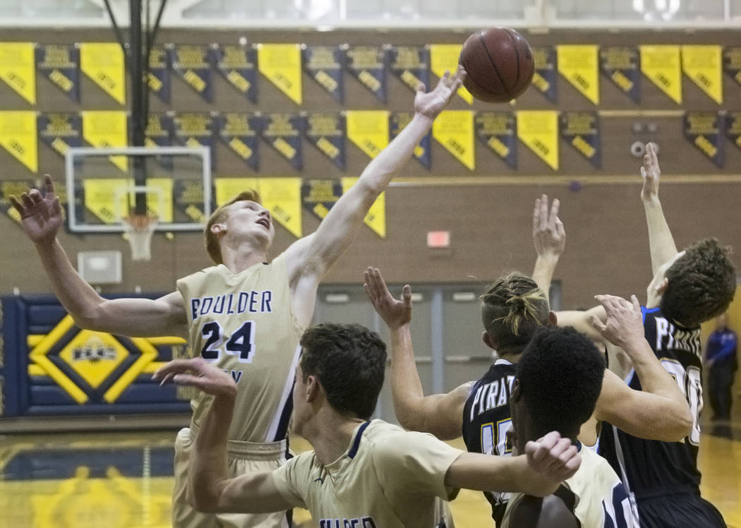 Boulder City sophomore guard Matt Morton (24) fights for a loose ball with Moapa Valley seni ...