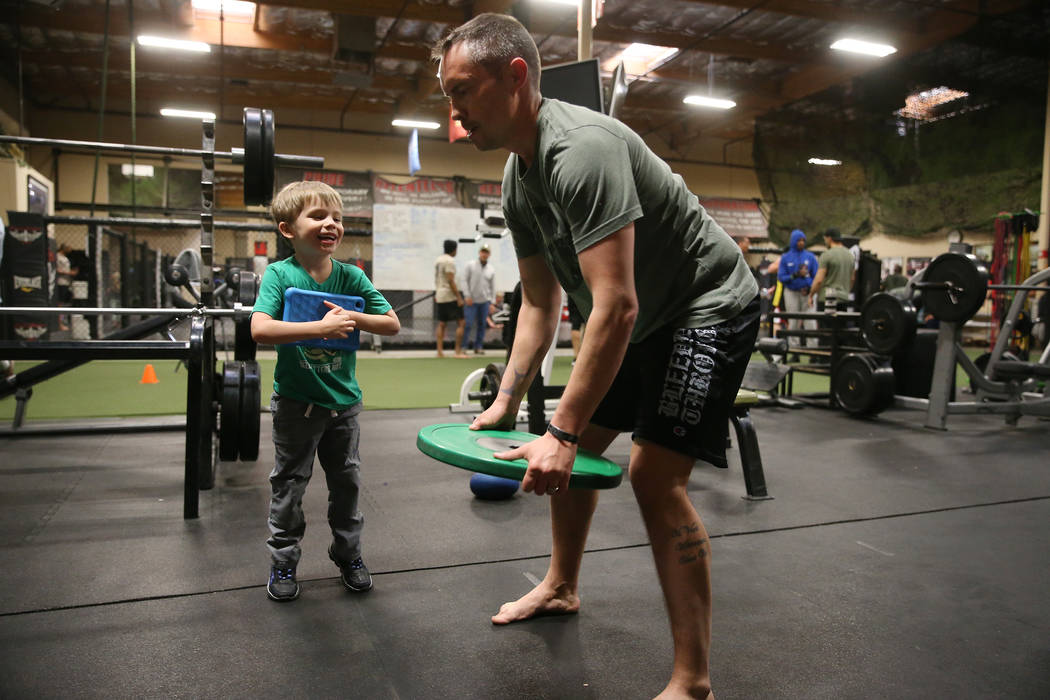 Military veteran Chris Jachimiec, right, works out as his son Cylas, 5, looks on, during a Merg ...