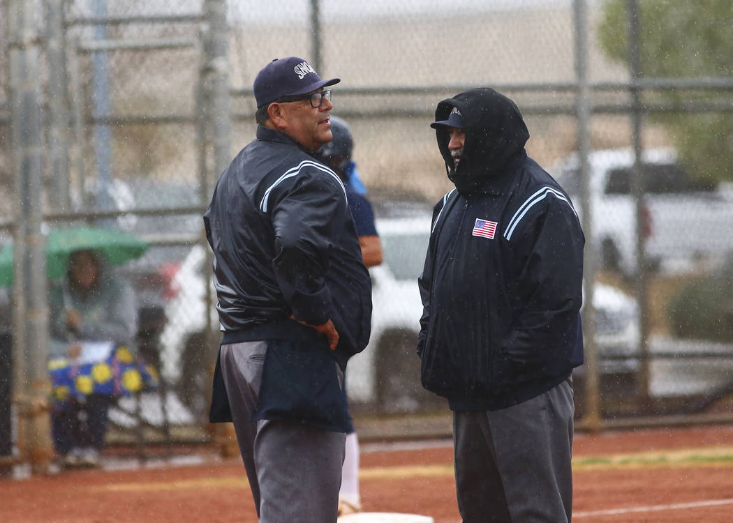 Umpires talk as rain comes down in the first inning of a softball game. (Chase Stevens/Las V ...