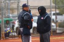 Umpires talk as rain comes down in the first inning of a softball game. (Chase Stevens/Las V ...