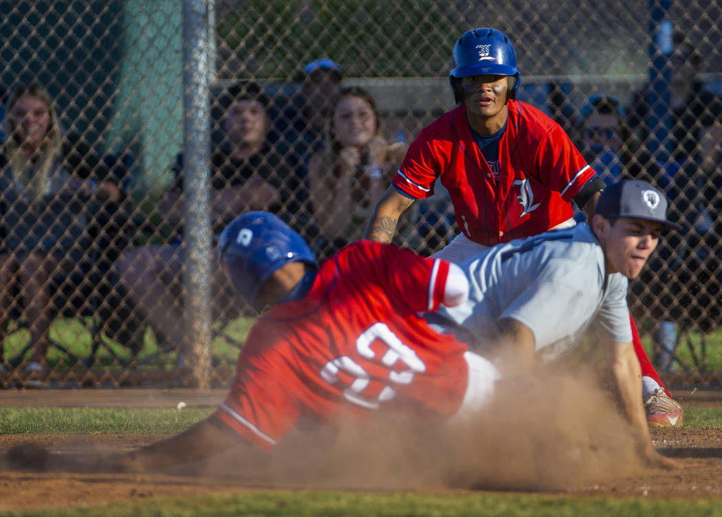 Liberty’s Mason Bowden (1) looks on as teammate Ky Yamamoto (23) slides safely into ho ...