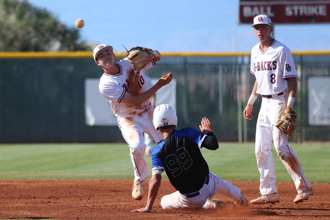 Desert Oasis’ Zac Czerniawski (8) looks on as Colby Smith (10) throws to first base fo ...