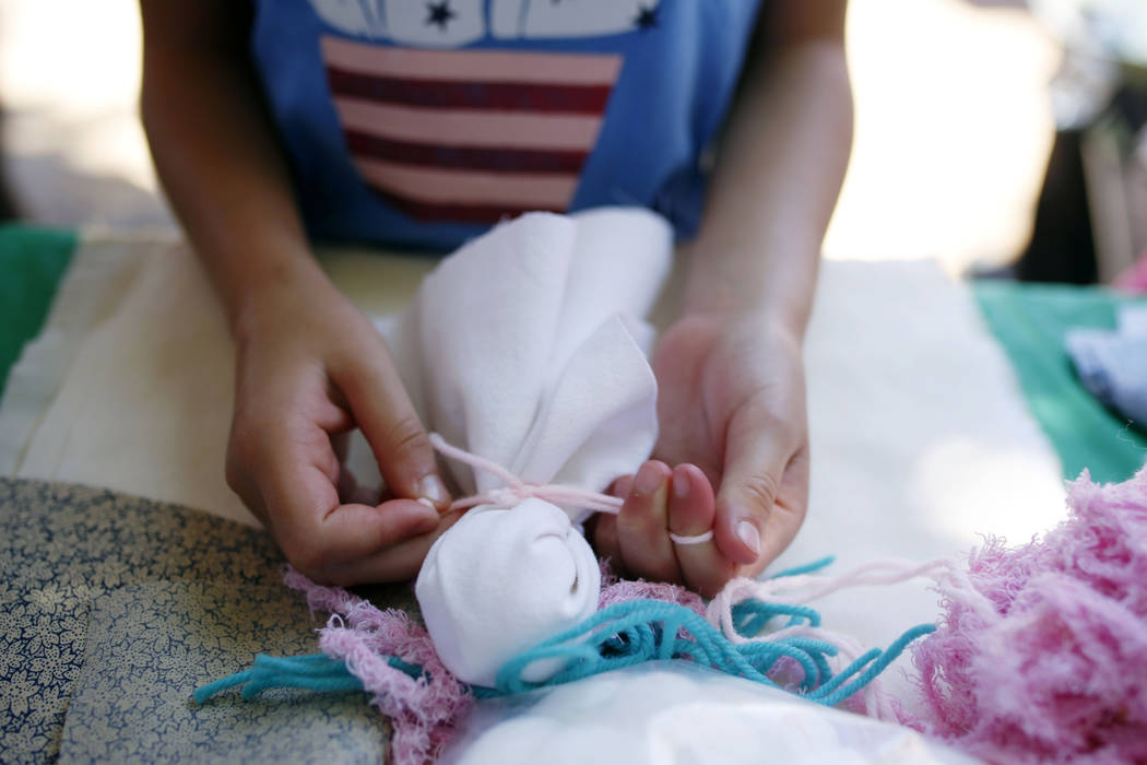 An attendee of Pioneer Day experiences life as a pioneer while making a pin doll at Old Mormon ...