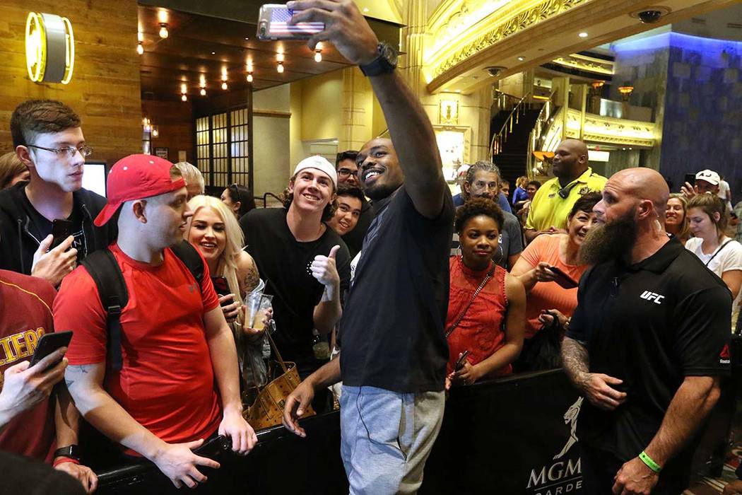 UFC light heavyweight champion Jon Jones holds up a cell phone to take a picture with a fan at ...