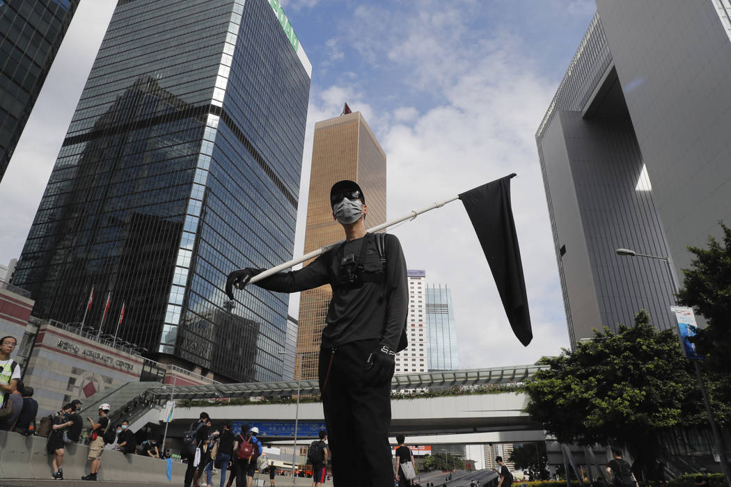 A protester holds a black flag to symbolize mourning for Hong Kong during a protest in Hong Kon ...