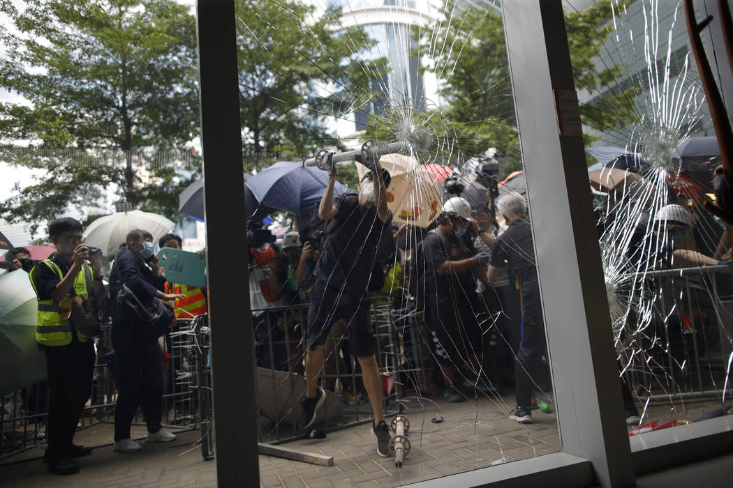A protester tries to break the glass to get into the Legislative Council in Hong Kong Monday, J ...