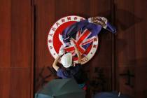 A protester covers the Hong Kong emblem with Hong Kong colonial flag after they broke into the ...