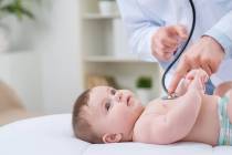 Pediatrician holding stethoscope and examining infant. (Getty Images)