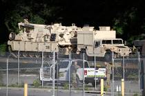 Military police stand military vehicles on a flat car in a rail yard, Monday, July 1, 2019, in ...