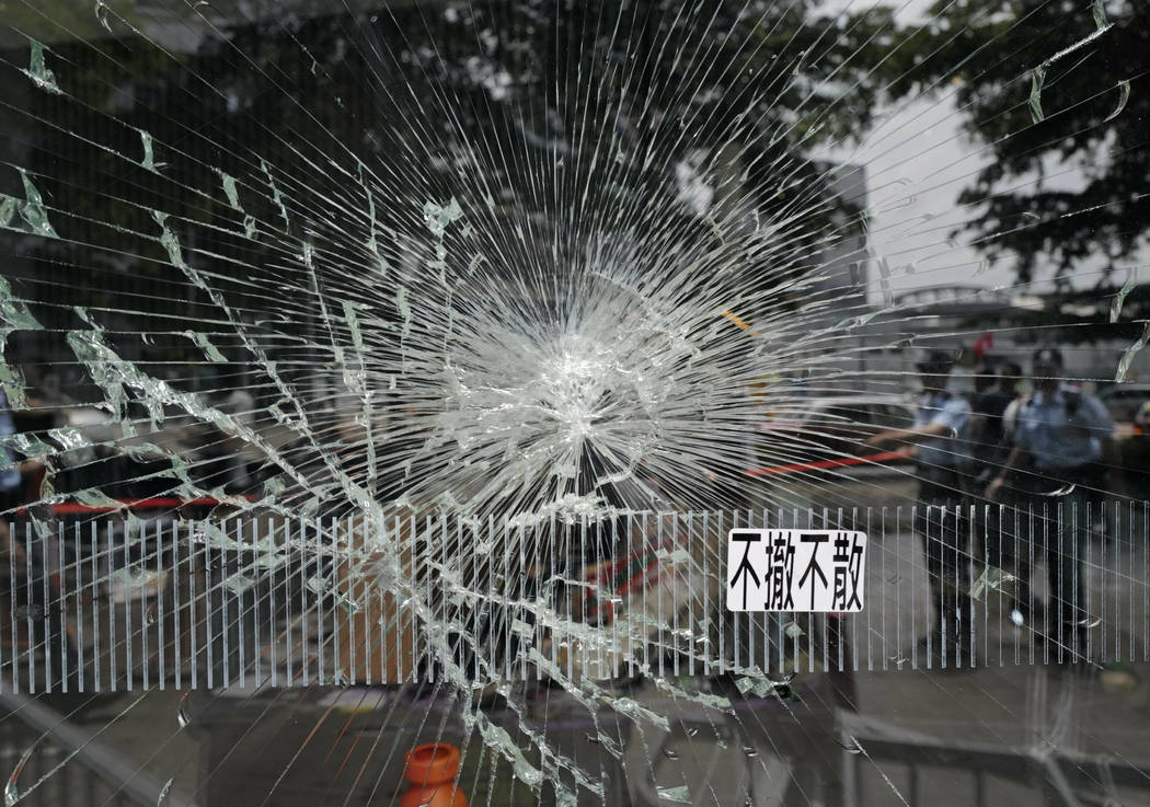 Police officers stand guard near a broken glass outside Legislative Council building in Hong Ko ...