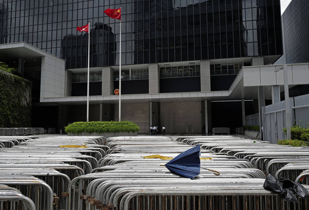 A broken umbrella is seen on barriers against a Hong Kong flag and a Chinese national flag at g ...