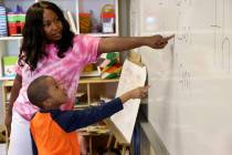 Kindergarten teacher Mo Fasehun and Joseph Dean work on sentences in her classroom during summe ...