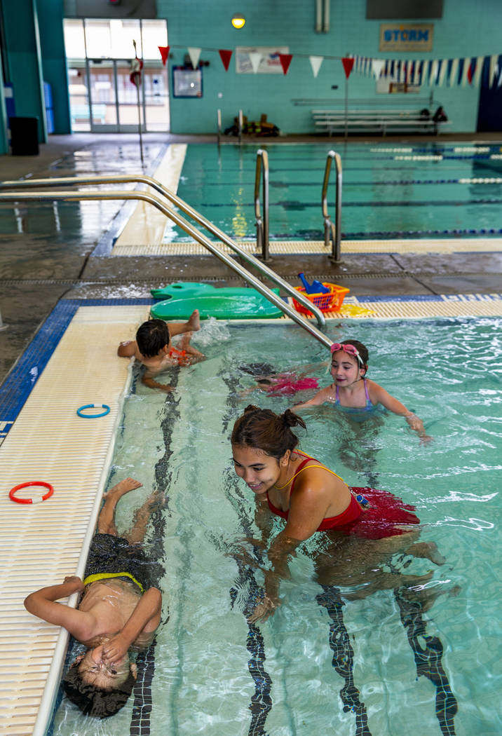 Swim instructor Shanneal Ocular, center, watches her students Stefan Flores, 4, foreground, try ...