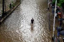 A man wades through a waterlogged street following heavy rains in Mumbai, India, Tuesday, July ...