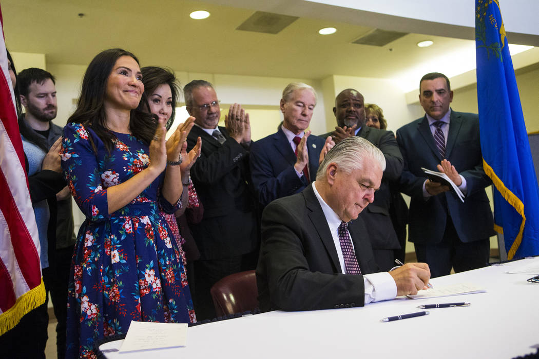 Assemblywoman Sandra Jauregui, D-Las Vegas, a survivor of Oct. 1, left, claps as Gov. Steve Sis ...