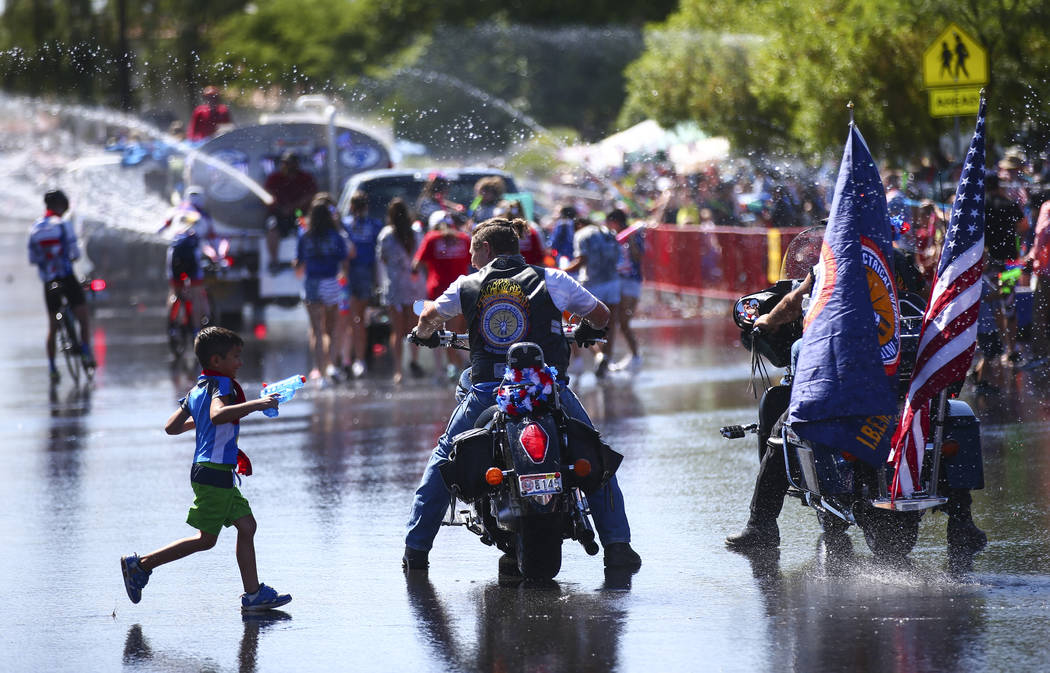 A child runs past a pair of parade participants on motorcycles, representing the International ...