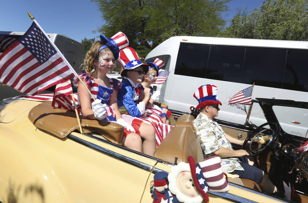 Parade goers wave to spectators in the crowd during the 25th annual Summerlin Council Patriotic ...