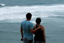 Dan Wong, left, and Cassie Tarleton watch waves crash along the coastline ahead of Hurricane La ...