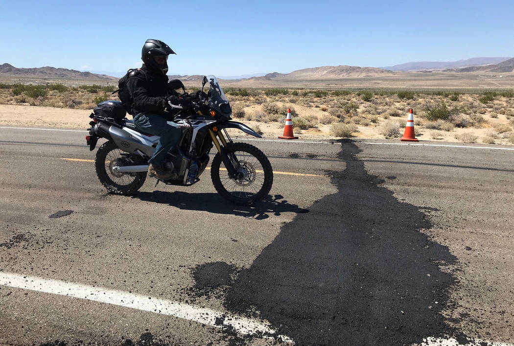 A motorcyclist rides over a temporarily repaired part of damage on Highway 178 in Ridgecrest, C ...