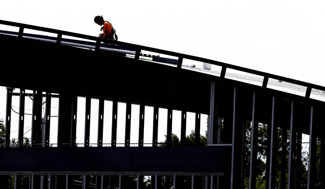 This photo taken Monday, July 1, 2019 shows a worker atop a new building under construction in ...