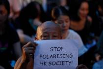 A man holds a card while joining a rally by mothers In Hong Kong on Friday, Jan. 5, 2019. Stude ...