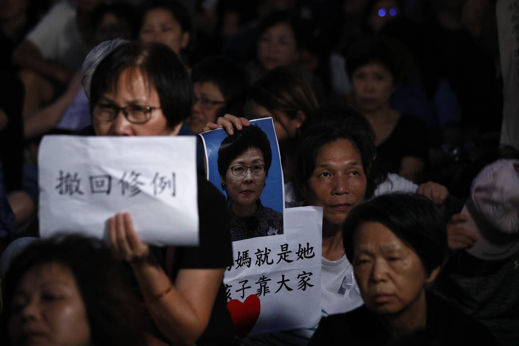 A woman holds a photo of Hong Kong Chief Executive Carrie Lam with the words "Black heart ...