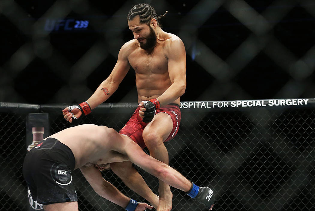 Jorge Masvidal, right, connects with a flying knee against Ben Askre in the first round during ...